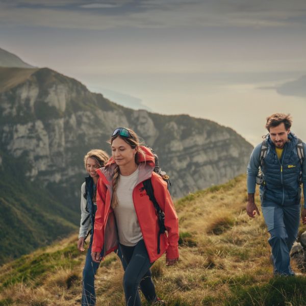 Three people in spring hiking outfits in a mountainous region.