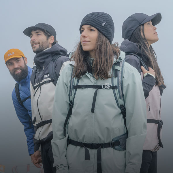 Four people are standing in foggy mountain scenery wearing weatherproof&nbsp;jackets.