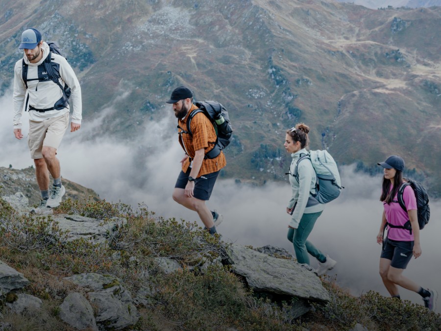 Two people in autumnal hiking gear are crossing a&nbsp;mountain